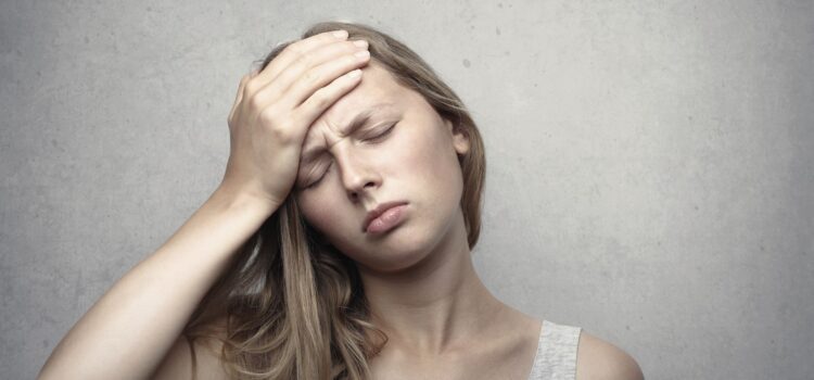 Neck Pain and Headaches: Is There a Connection? A woman in distress holding her head, expressing emotion and fatigue.